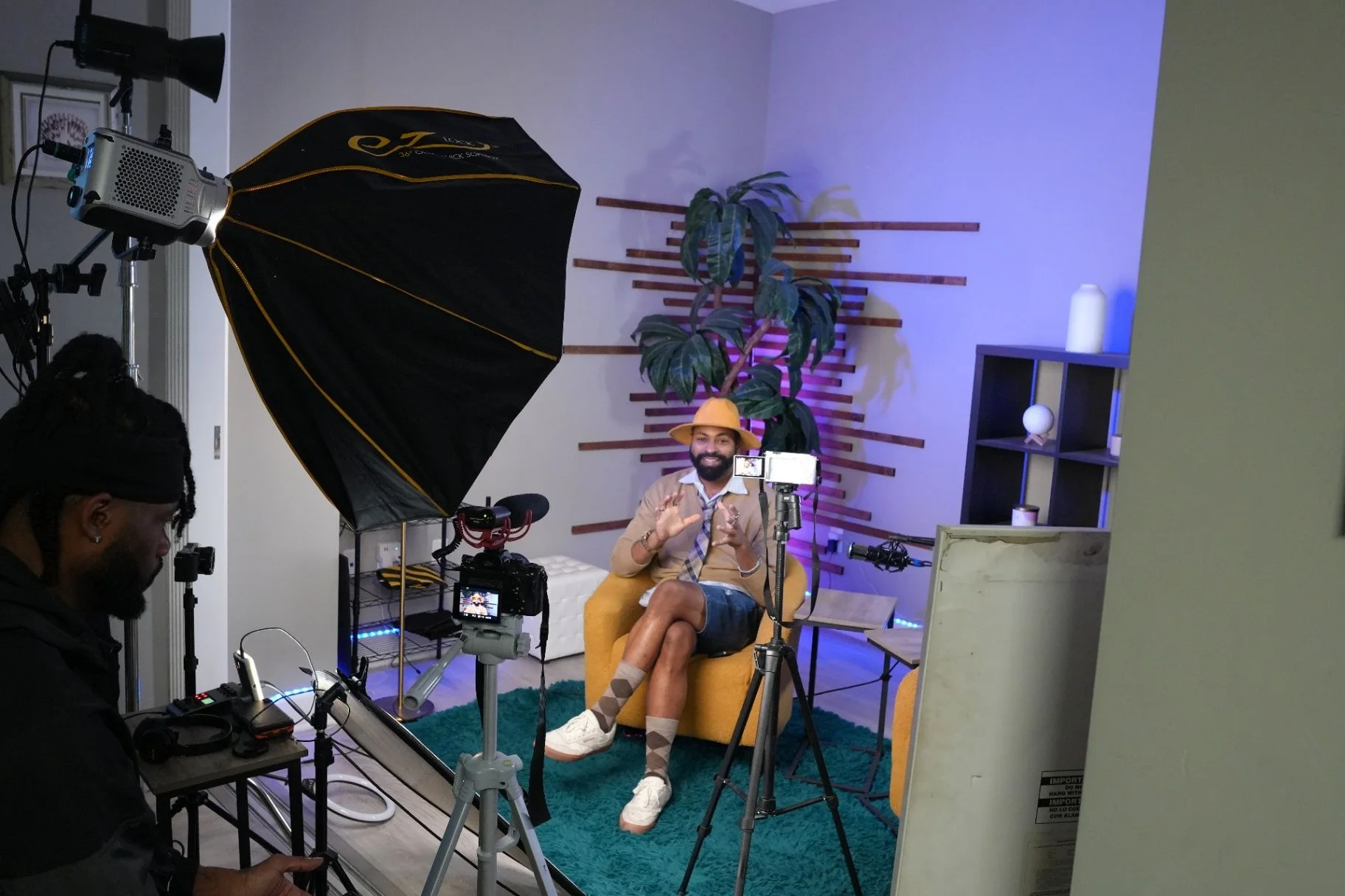 Recorded conversation in a podcast studio with a guest seated beneath a softbox and surrounded by cameras and microphones.